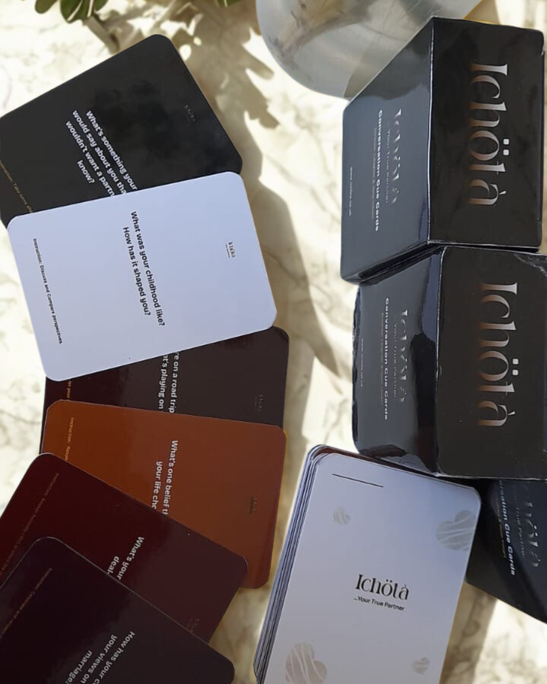 Cue card decks and their black slipcases laid out on sunlit marble